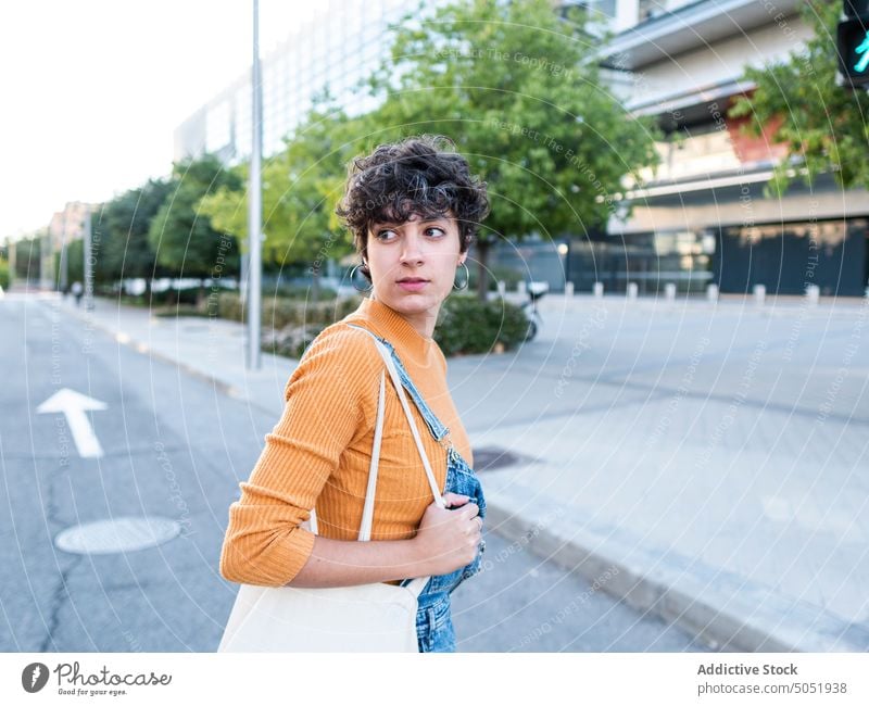 Frau mit Einkaufswagen auf der Straße lässig Stil Käufer Gebäude Spaziergang Großstadt positiv urban jung Kurze Haare mehrstöckig Revier modern dunkles Haar