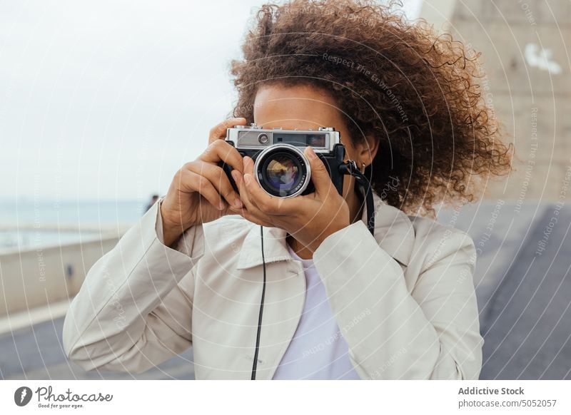 Schwarze Frau mit Fotokamera Tourist Urlaub Straße Stil krause Haare Reise reisen Dame trendy Sommer sorgenfrei tagsüber Afro-Look Vergnügen lässig jung Outfit