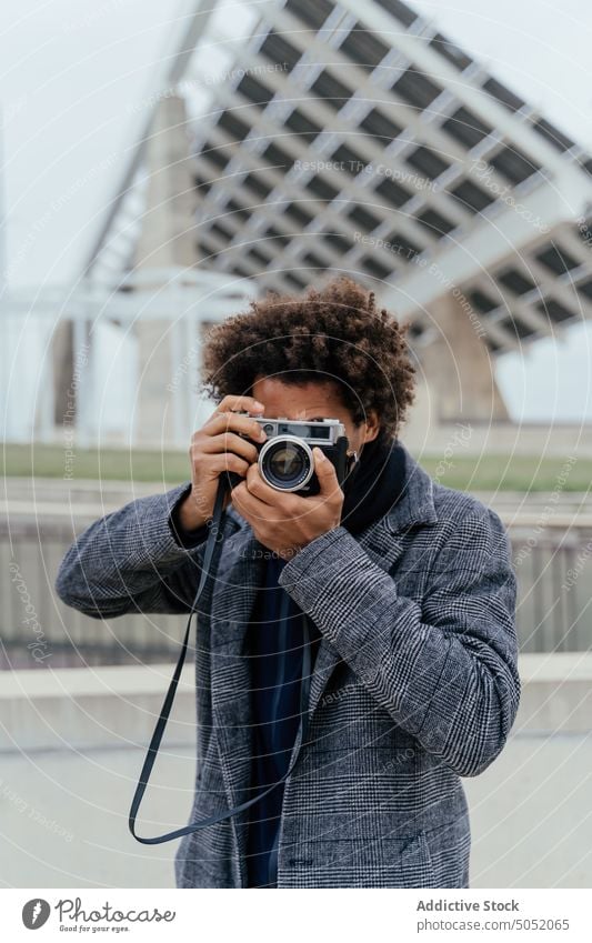 Schwarzer Mann mit Fotokamera Tourist Urlaub Straße Stil Afrohaar Reise reisen trendy Sommer sorgenfrei tagsüber Afro-Look Vergnügen lässig jung Outfit