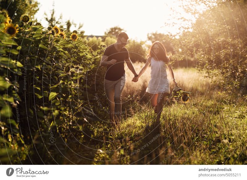 Schönes Paar hat Spaß im Sonnenblumenfeld. Ein Mann und eine Frau in der Liebe Spaziergang in einem Feld mit Sonnenblumen, ein Mann umarmt eine Frau. selektiven Fokus