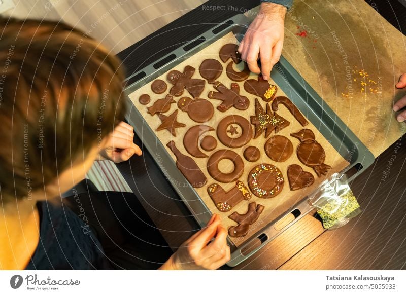 Eine Frau und ein Mann dekorieren vor Weihnachten einen festlichen Ingwerkeks Lebkuchenplätzchen Cookies Keks Gebäckstück Lebkuchenkuchen Weihnachtskuchen