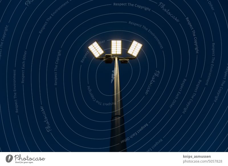 Eine Flutlichtanlage bei Nacht. Ein angeschalteter Flutlichtmast bei Nacht. Lichtmast Flutlichtspiel Beleuchtung Sportplatz Sportanlage Stadion Aussenaufnahme