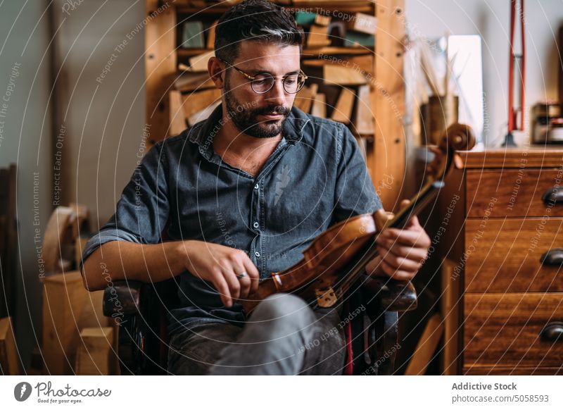 Männlicher Geigenbauer mit Geige in der Werkstatt Mann Instrument Zupfinstrumentenmacher Basteln Atelier professionell klassisch Arbeitsplatz Kunsthandwerker