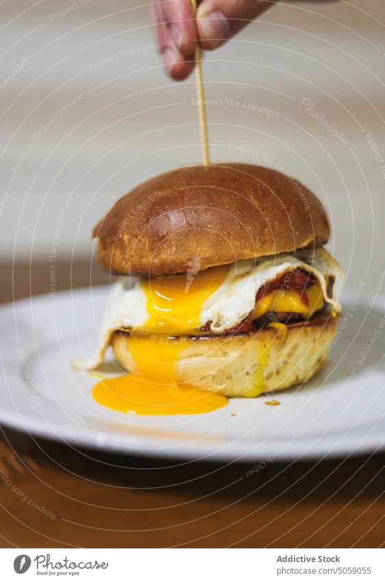 Leckere frisch zubereitete Burger auf dem Teller Person Hamburger lecker Zahnstocher Ei Brötchen Lebensmittel Fastfood dienen Tisch geschmackvoll Mahlzeit