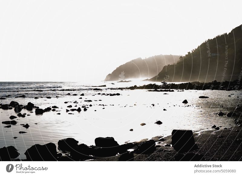 Sonnenbeschienener steiniger Strand bei Sonnenaufgang Ufer Kieselsteine Klippe MEER Wolkenloser Himmel sonnenbeschienen malerisch Morgen Natur Alkolea-Strand