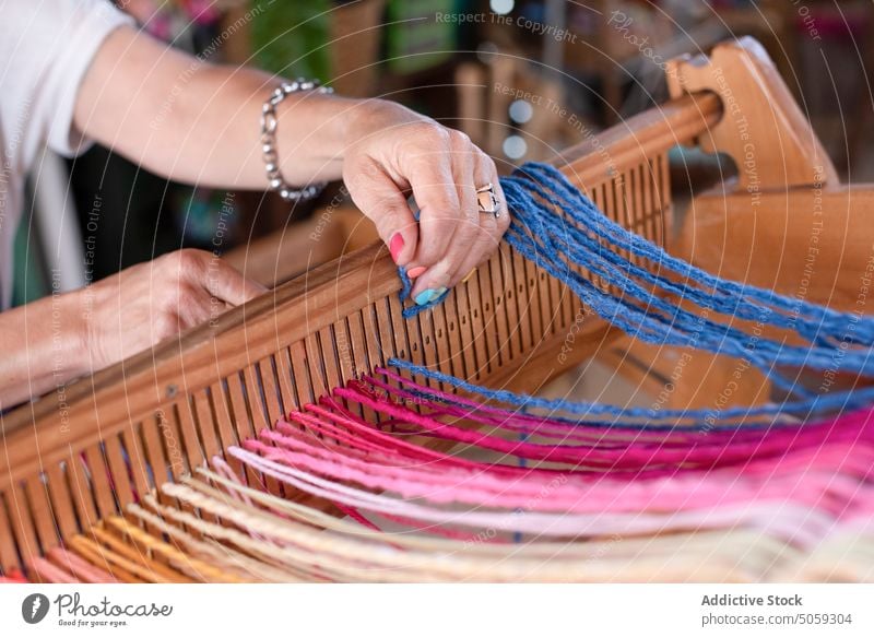 Unbekannter Kunsthandwerker bei der Arbeit mit Garn am Webstuhl Handwerkerin Faser Basteln Weben Atelier Schilfrohr Schlitz Frau Werkstatt Kleinunternehmen