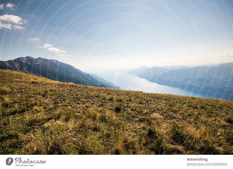 Blick vom Monte Baldo auf den Gardasee See Natur Landschaft Aussicht Italien Berg Gebirge Gipfel Wiese Himmel Weite Gras Wasser Sonne gelb blau Wolken Horizont