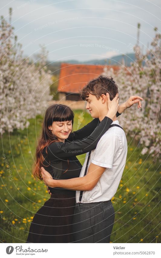 Junge starke Liebe zwischen zwei jungen Menschen, die unter Apfelbäumen spazieren gehen. Unverfälschtes Porträt eines Paares in Freizeitkleidung. Zuneigung von zwei Menschen