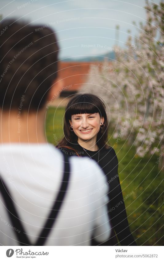 Junge starke Liebe zwischen zwei jungen Menschen, die unter Apfelbäumen stehen. Unverfälschtes Porträt eines Paares in Freizeitkleidung. Zuneigung von zwei Menschen. Lächeln eines Mädchens über die Liebe ihres Lebens