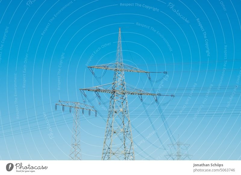 hohe Energiekosten, Strommast auf Feld vor blauem Himmel energiekostenanstieg strommast stromleitung energiekrise erneuerbare energie feld landschaft