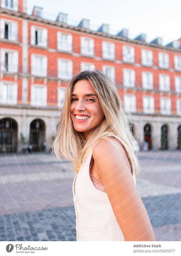 Optimistische Frau geht auf Platz Spaziergang Quadrat Stil Glück Lächeln Straßenbelag Wochenende Vorschein jung blond Outfit heiter froh positiv schlendern