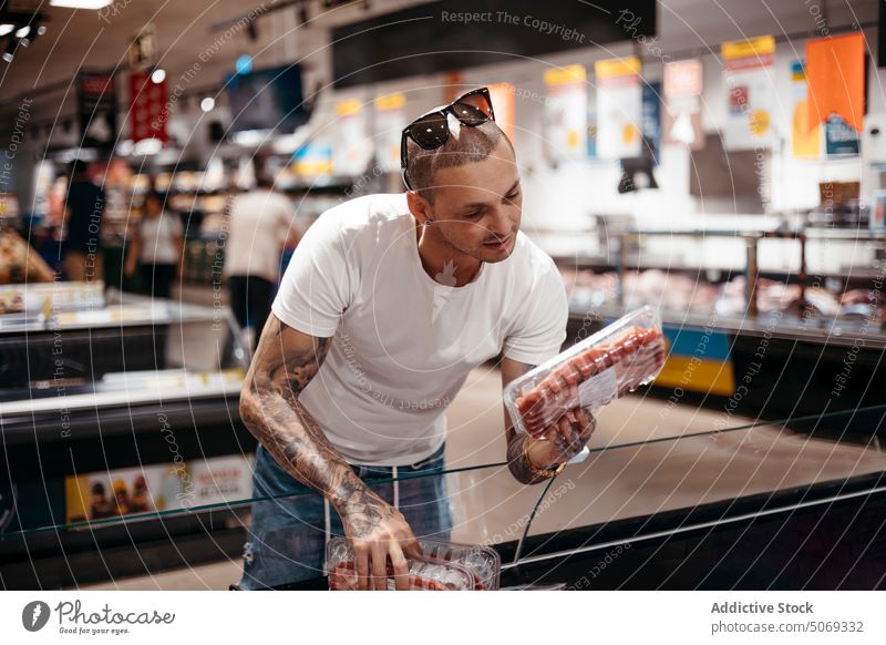 Mann wählt Fleisch im Lebensmittelgeschäft aus Supermarkt pflücken wählen Kunde Steak frieren Käufer Klient Laden Kauf Wahl lässig kaufen Lifestyle Produkt