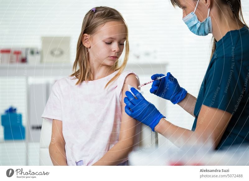 Weibliche Krankenschwester mit chirurgischer Maske und in Handschuhen gibt einem Teenager in der Klinik eine Impfstoffinjektion. Kinderimpfung. Antibiotikum