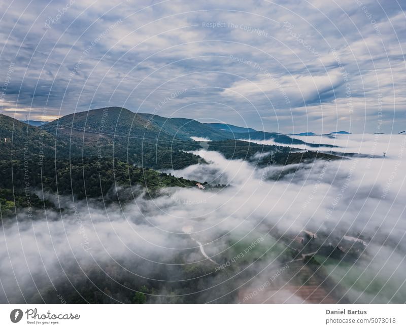 Panoramablick auf das alte Dorf Mirmande in Frankreich. Luftaufnahme am Morgen im dichten Nebel, der um die Stadt aufsteigt Tier Hintergrund blau hell kalt