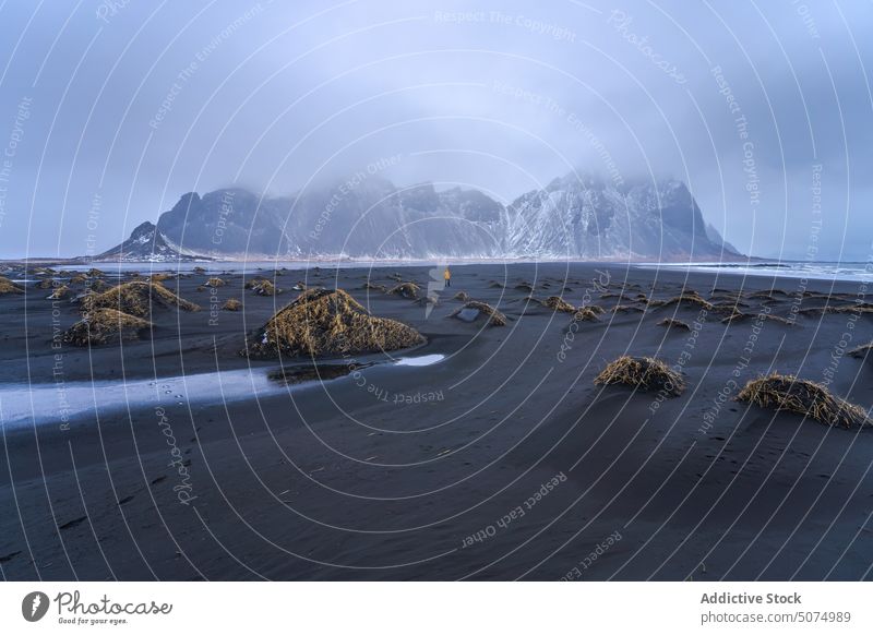 Unbekannter Reisender am Sandstrand stehend Strand Bevorratung Ufer winken MEER Vestrahorn Berge u. Gebirge Natur Landschaft Island schwarz Tourist Himmel