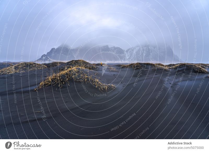 Unbekannter Reisender am Sandstrand stehend Strand Bevorratung Ufer winken MEER Vestrahorn Berge u. Gebirge Natur Landschaft Island schwarz Tourist Himmel