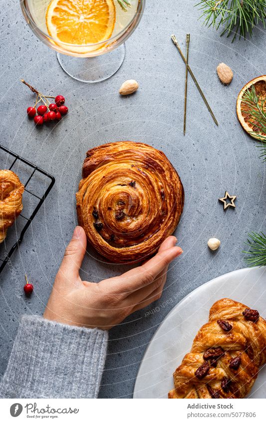 Person, die gebackenes Gebäck vom Weihnachtstisch nimmt Lebensmittel Zopf süßes Brötchen Hand Teller Weihnachten Dekoration & Verzierung selbstgemacht Kiefer