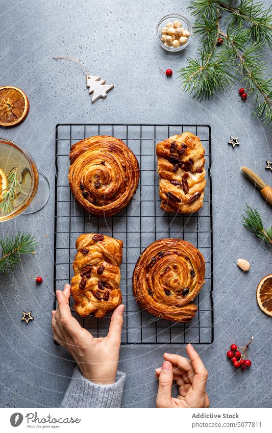 Person, die gebackenes Gebäck vom Weihnachtstisch nimmt Lebensmittel Zopf süßes Brötchen Hand Teller Weihnachten Dekoration & Verzierung selbstgemacht Kiefer