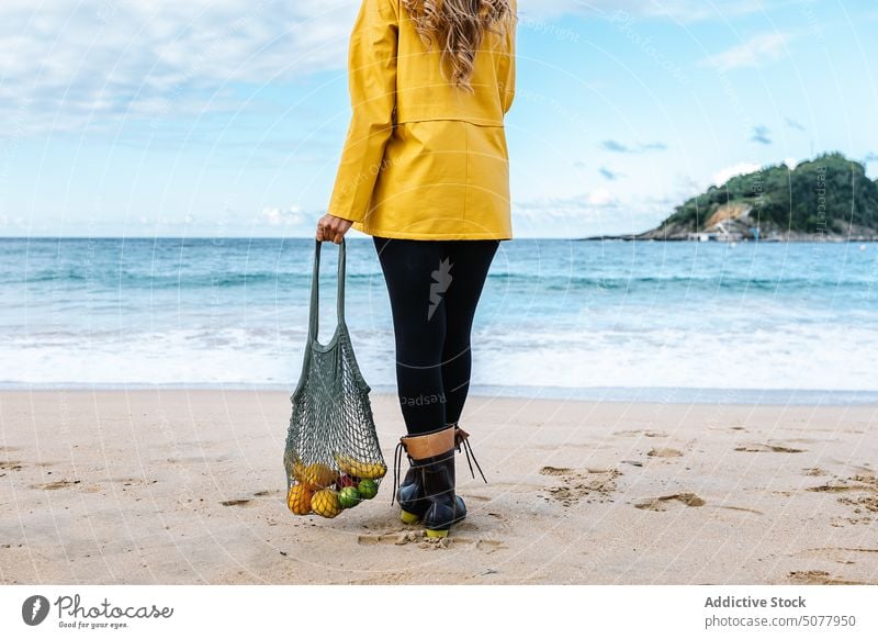 Frau mit Obst in der Tasche bewundert den Strand Frucht winken MEER Stehen sandig Wasser Apfel organisch Küste donostia Urlaub bewundern Natur Spanien nass