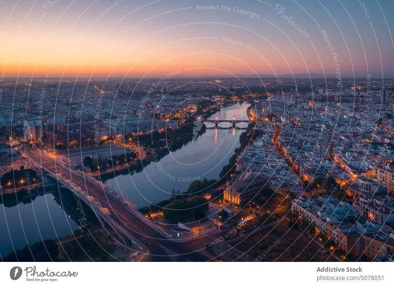 Leuchtendes Stadtbild mit sich im Fluss spiegelnden Gebäuden bei Sonnenuntergang in Spanien Sevilla glühen Zentrum Andalusia Abend Brücke Wasser historisch