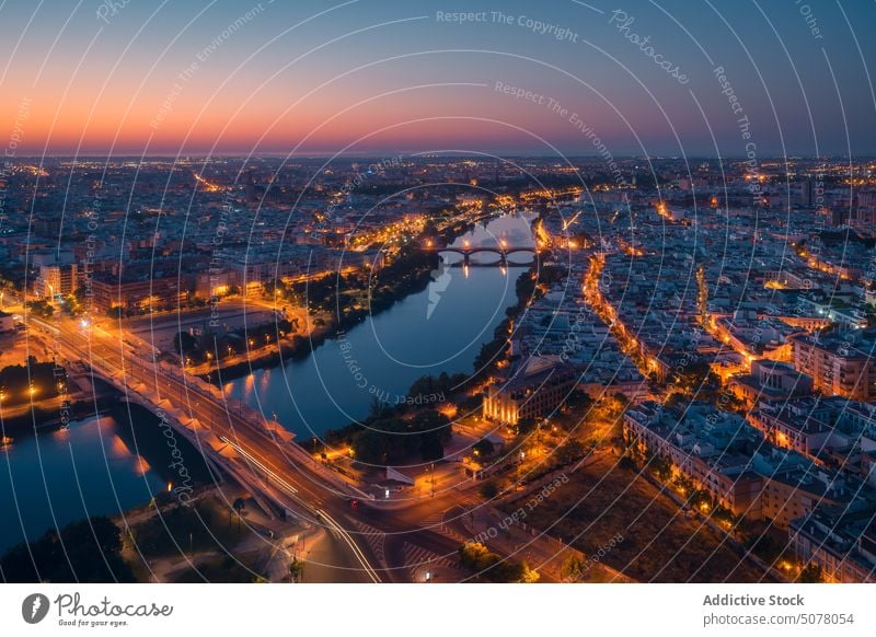 Leuchtendes Stadtbild mit sich im Fluss spiegelnden Gebäuden bei Sonnenuntergang in Spanien Sevilla glühen Zentrum Andalusia Abend Brücke Wasser historisch