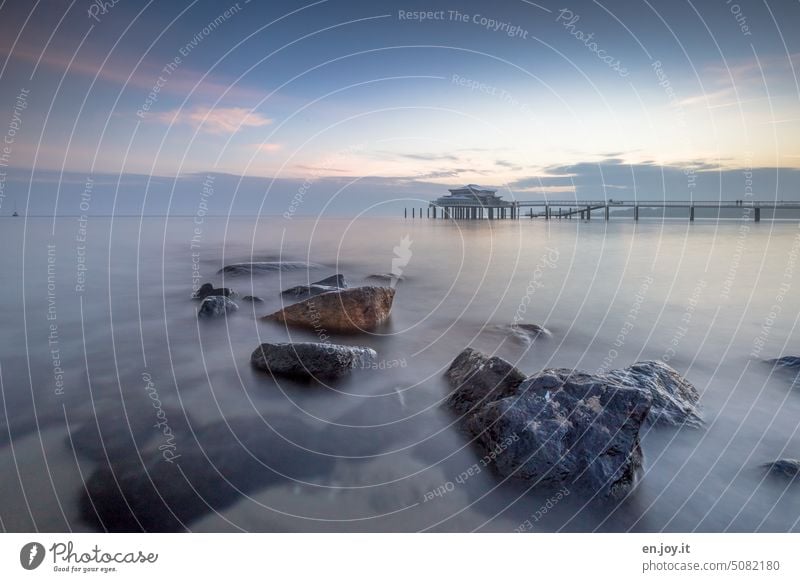 Teehaus am Timmendorfer Strand mit Felsen im Vordergrund Meer Seebrücke Horizont Morgenstimmung ruhig Langzeitbelichtung Wasser klar Himmel Ostsee