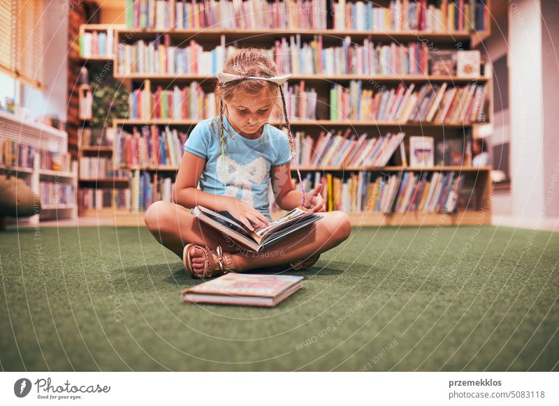 Grundschülerin macht Hausaufgaben in der Schulbibliothek. Schülerin lernt aus Büchern. Schülerin studiert interessante Bücher. Zurück zur Schule Rücken