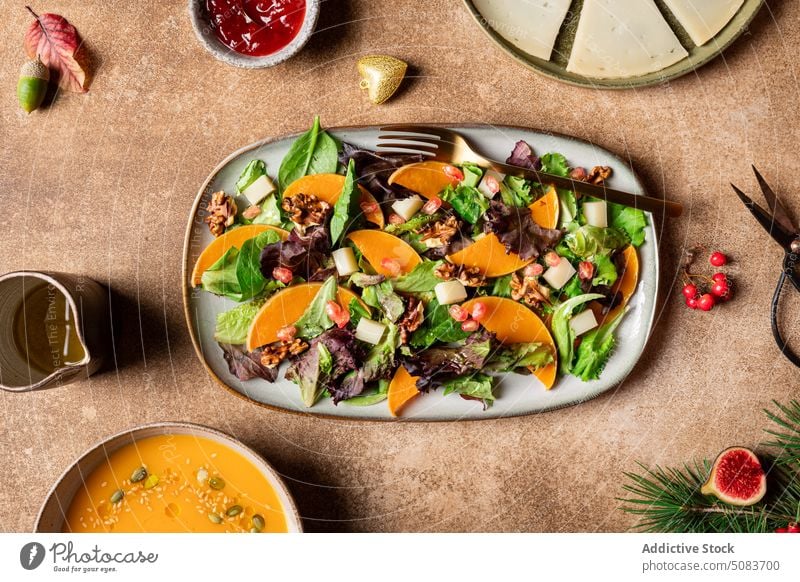 Teller mit vegetarischem Salat zum Mittagessen Salatbeilage Kürbis Spinat Veganer Gemüse gesunde Ernährung dienen Samen Granatapfel Walnussholz Saucen Beeren