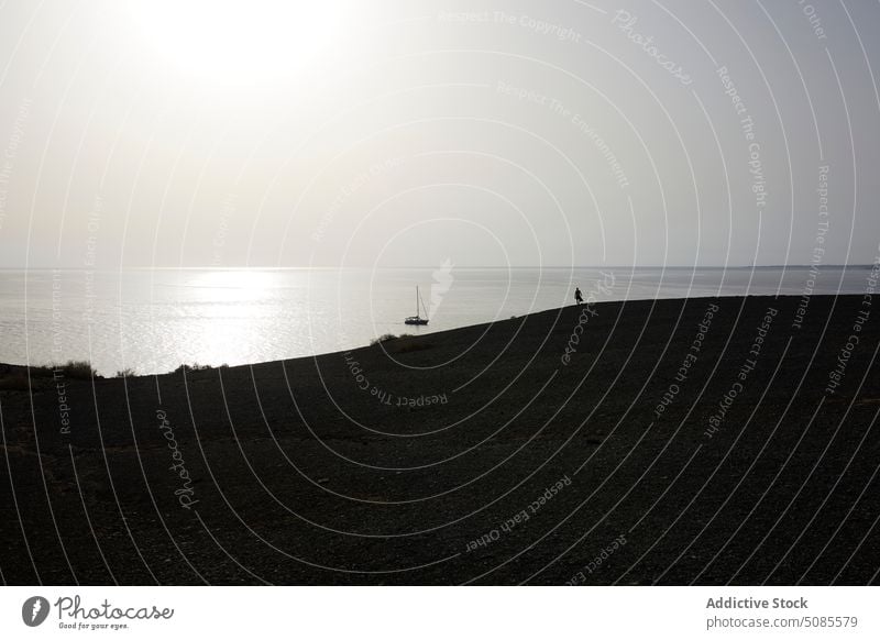 Anonyme Person bewundert das Meer von einem Hügel aus unter dem Himmel bei Sonnenuntergang bewundern Tourist Silhouette Natur Strand Landschaft atemberaubend