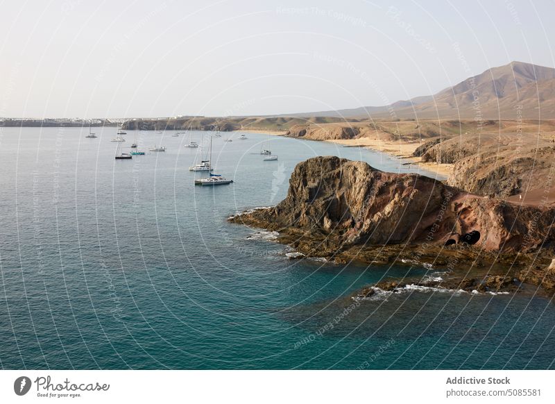 Boote segeln im Meer in der Nähe von felsigen Klippen im Sonnenlicht MEER vulkanisch Segelboot Natur Meereslandschaft Insel malerisch atemberaubend Ufer Küste