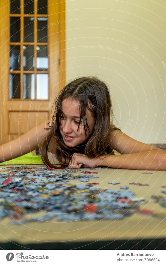 Ein brünettes Teenager-Mädchen, das auf dem Boden ihres Hauses ein Puzzle macht. Sie verbringt ihre Zeit damit, der Technologie zu entfliehen und traditionelle Spiele zu genießen.