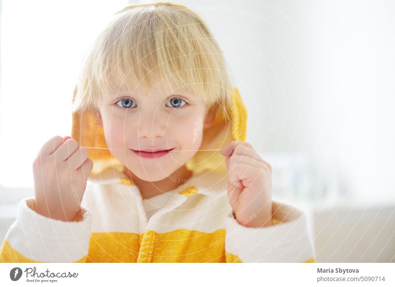 Vorschüler Junge gereinigt Zähne mit Zahnseide und dann ist das Putzen seiner Zähne mit Zahnbürste sorgfältig. Kinder lernen die richtige Mundhygiene. Zahnmedizin und Gesundheitsfürsorge für Kinder