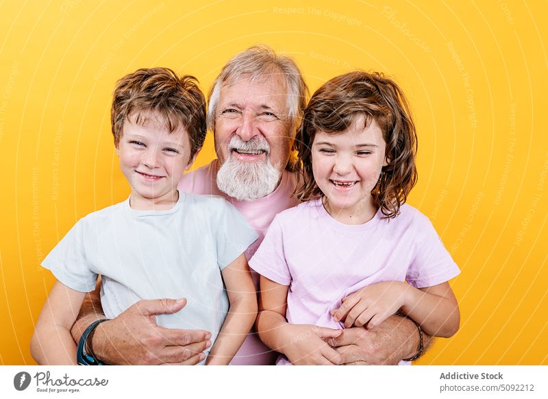 Glücklicher Großvater mit Enkelkindern auf gelbem Hintergrund Mann Umarmen Umarmung Lachen Liebe schließen Bonden Partnerschaft genießen Lächeln heiter positiv