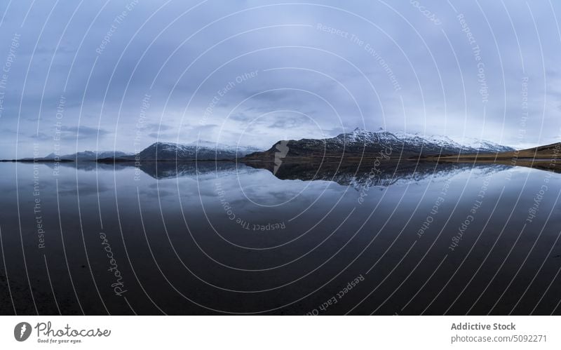 Gefrorener See in der Nähe eines verschneiten Hochgebirges gefroren Schnee hoch Berge u. Gebirge ruhig Eis Gelände bedeckt wolkig Himmel grau Formation kalt