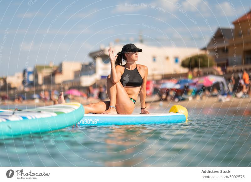 Gesunde Frau sitzt auf einem Paddelbrett und macht Yoga üben Asana Zusatzplatine MEER Natur Wasser Harmonie Resort Sommer Aktivität vakrasana