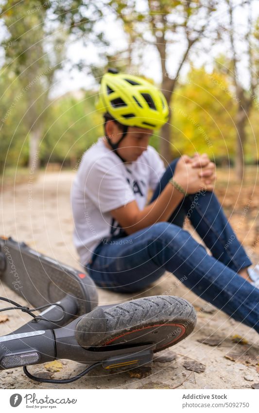 Jugendlicher fiel vom Elektroroller und hatte Schmerzen Teenager Junge fallen elektrisch Tretroller Verletzung wehtun Knie Problematik jung sitzen Boden Unfall