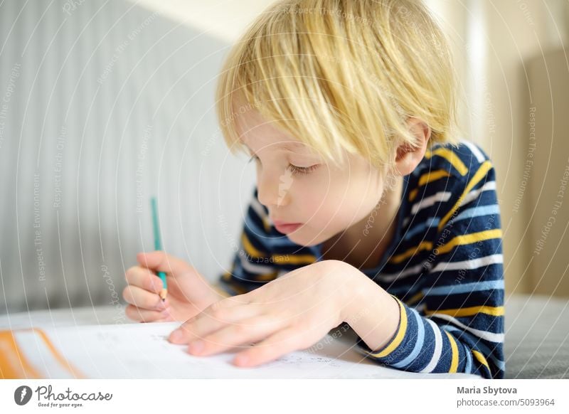 Grundschüler Junge macht Hausaufgaben zu Hause. Kind lernt zu zählen, löst arithmetische Beispiele, macht Übungen im Arbeitsbuch. Mathe-Tutorial. Preparing Vorschüler Baby für die Schule. Bildung