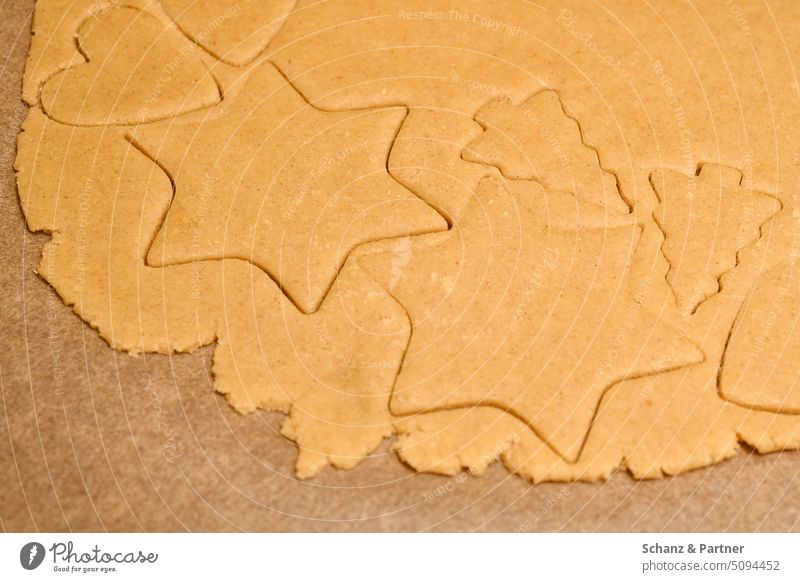 ausgestochener roher Teig in Sternform für Weihnachtsplätzchen auf Backpapier Weihnachtsgebäck Gebäck Plätzchen Backen Weihnachten & Advent Plätzchen ausstechen