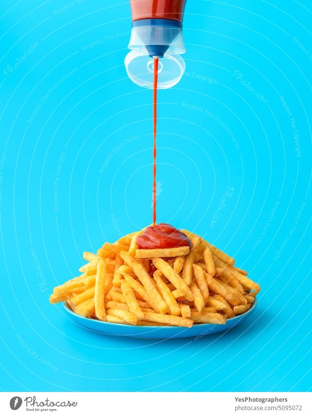 Ketchup-Sauce über Pommes frites gießen, isoliert auf blauem Hintergrund Überfluss hell Kalorien Farbe Konzept Textfreiraum Knusprig Küche ausschneiden