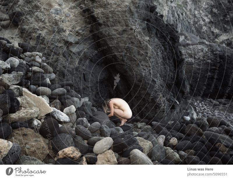 Ein unwegsames Gelände mit riesigen Felsen und Steinen. Eine Küstenlinie neben ein paar massiven Bergen. Und ein wunderschönes nacktes Mädchen, das sich versteckt. Ihre sexy Kurven lassen sich allerdings nicht so leicht verstecken.