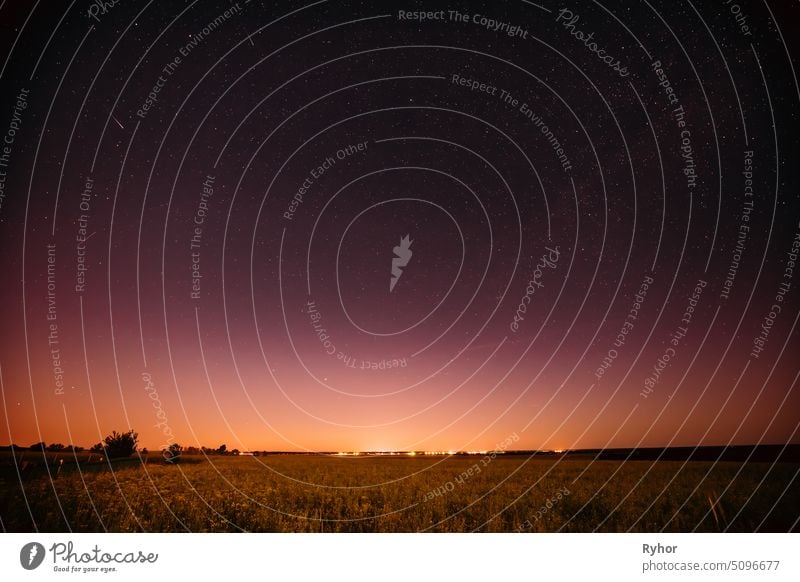 Natürliche Nacht Sternenhimmel über Sommer Feld Wiese. Glühende Sterne, Meteoritenweg und Sonnenuntergang Sonnenaufgang Lichter über Wiese Landschaft