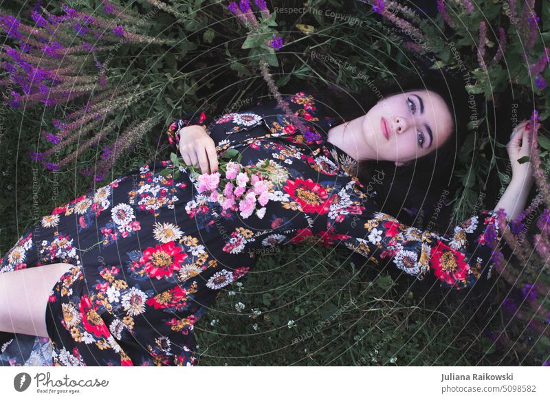 schöne Frau im Sommerkleid liegt auf einer Blumenwiese Stil einzigartig trendy Frühling Frauengesicht Beautyfotografie nachdenklich Lifestyle Gesicht Porträt