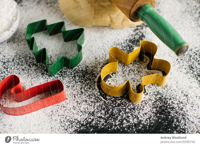 Bunte, weihnachtliche Ausstechformen auf einem mit Mehl bestäubten Tisch backen Zuckerstange Feier Kindheit Kinder Weihnachten Weihnachtsbaum Nahaufnahme Keks