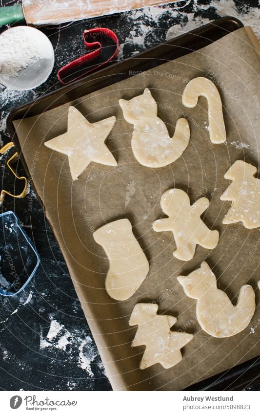 frisch ausgestochene Zuckerplätzchen auf einer Backform verteilt backen Backblech schwarz Zuckerstange Feier Kindheit Kinder Weihnachten Weihnachtsbaum