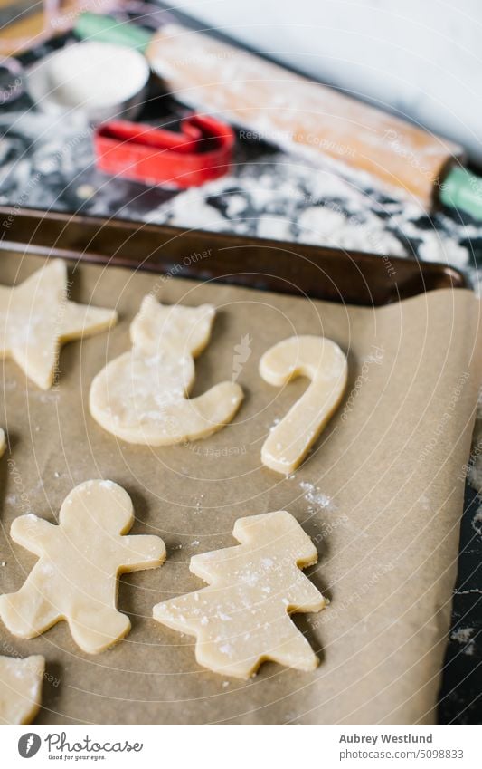 Frisch ausgestochene Zuckerplätzchen auf einem Plätzchenblech verteilt backen Backblech schwarz Zuckerstange Feier Kindheit Kinder Weihnachten Weihnachtsbaum