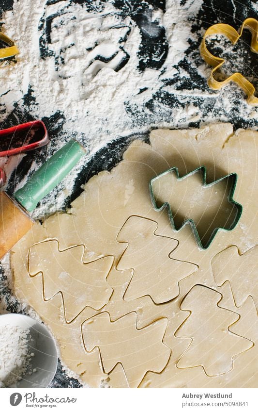 Ausstechen von Weihnachtsbaumplätzchen aus frisch gepresstem Teig backen Backblech schwarz Zuckerstange Feier Kindheit Kinder Weihnachten Nahaufnahme Keks