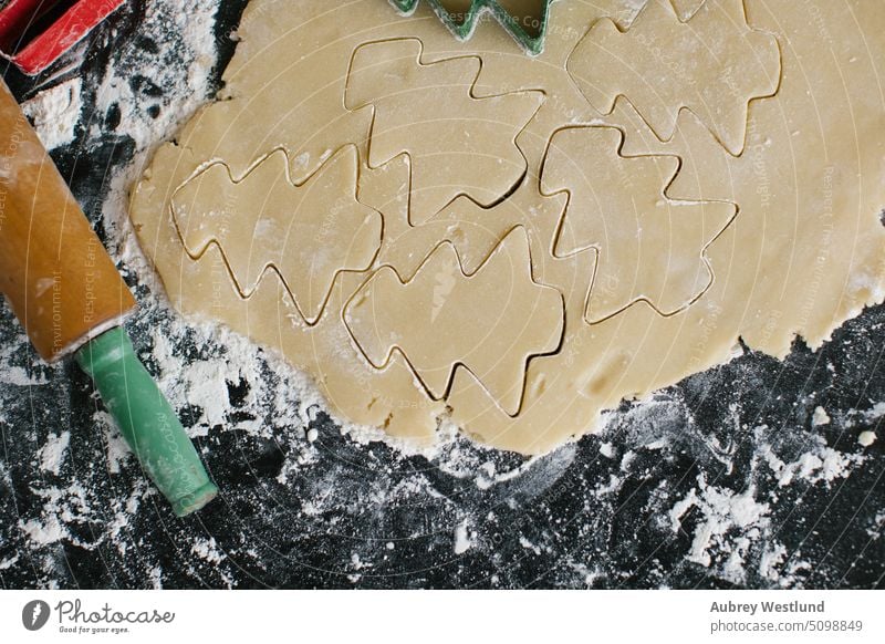 Ausstechen von Weihnachtsbaumplätzchen aus frisch gepresstem Teig backen Backblech schwarz Zuckerstange Feier Kindheit Kinder Weihnachten Nahaufnahme Keks