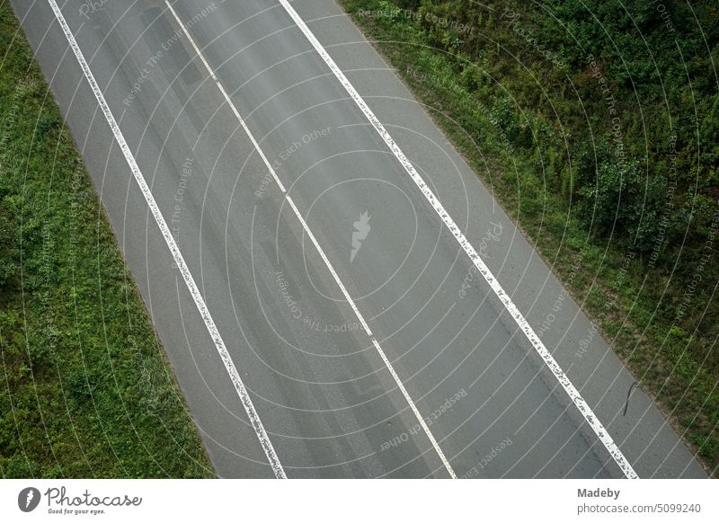 Fahrbahnmarkierung mit Überholverbot auf grauem Asphalt und Standstreifen in Oerlinghausen bei Bielefeld am Hermannsweg im Teutoburger Wald in Ostwestfalen-Lippe