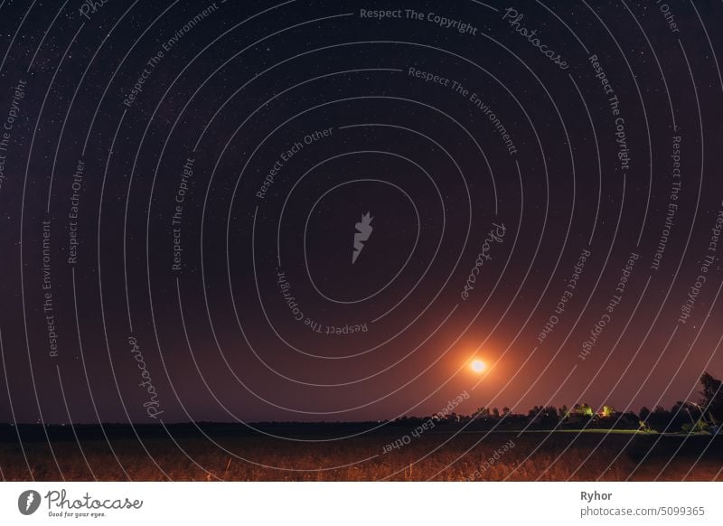 Mondaufgang über weißrussischen Dorf in Osteuropa. Weißrussische Landschaft im Sommer sternenklarer Nacht im Freien kosmisch Szene Raum Glühende Sterne Natur