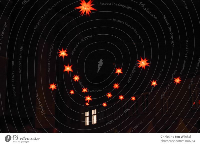 Leuchtend rote Herrnhuter Sterne und zwei hell erleuchtete Fenster in der Dunkelheit Weihnachtsbeleuchtung Weihnachtsmarkt Lichterschein Lichterglanz Fassade